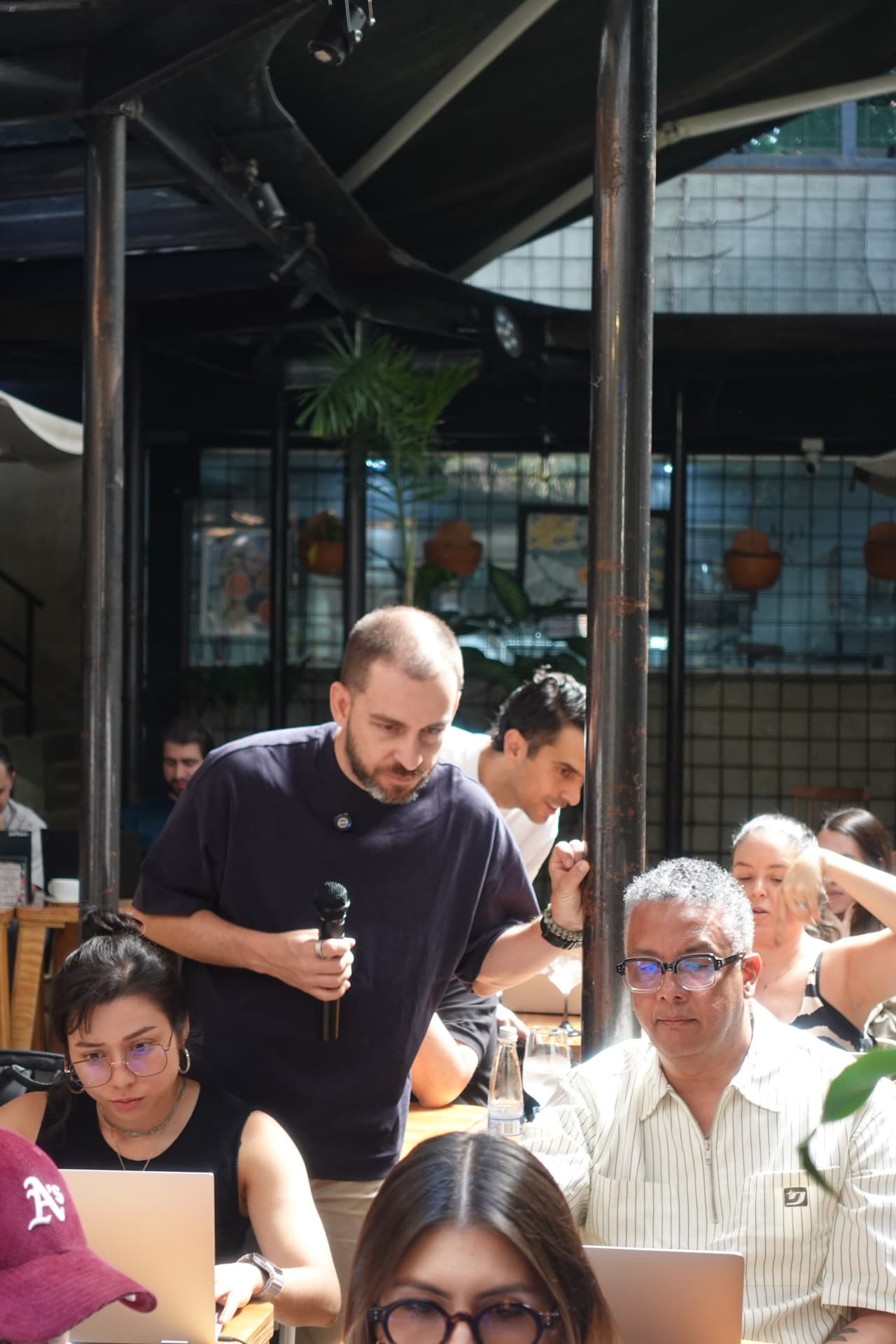 Un facilitador con micrófono se inclina entre los asistentes para revisar el trabajo en sus pantallas