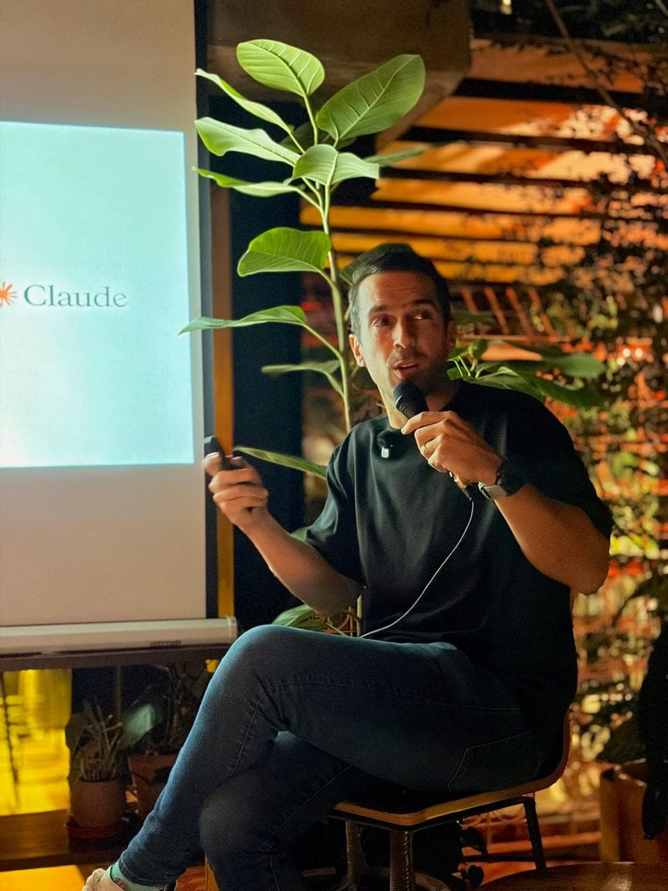 Un ponente explica con el micrófono en la mano frente a una diapositiva con el logotipo de Claude